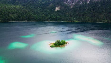 Drone-shot-reveals-beautiful-Island-in-Lake-Eibsee-at-the-base-of-mountain-Zugspitze,-Scenic-lake-in-the-mountains,-Germany