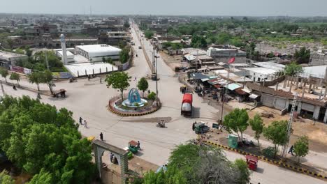 Aerial-roundabout-Badin-city-centre-with-light-traffic,-Sindh-rural-Pakistan