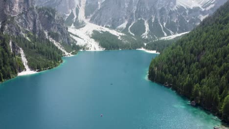 Tilt-up-from-tranquil-waters-to-majestic-Dolomite-peaks-at-lake-Braies,-Italy