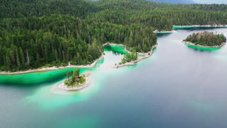 Drone-shot-revealing-small-islands-at-Lake-Eibsee-in-Bavaria-Alps-at-the-base-of-Zugspitze-mountain,-Scenic-mountain-landscape-and-pine-tree-forest,-Germany