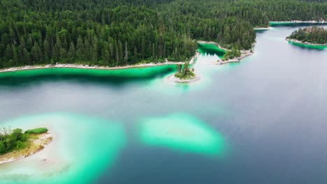 An-aerial-view-of-a-luminescent-turquoise-lake,-with-islands,-surrounded-by-emerald-pine-trees
