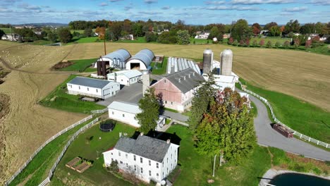 Pennsylvania-farm-in-autumn:-white-farmhouse,-barns,-silos,-and-harvested-fields