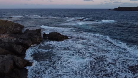 Aerial-FPV-fly-over-ocean-full-wave-crash-shore,-sunset