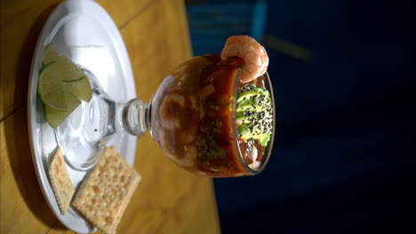 Vertical-shot-of-a-seafood-shrimp-cocktail-served-in-a-glass-cup-with-avocado-and-some-shrimp-on-top