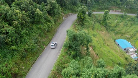 Aerial-tracking-shot-of-car-driving-on-road-in-suburb-area-of-Nepal