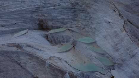 Aerial-birds-eye-view-of-Pamukkale-white-cotton-castle-carbonate-mineral-terraces-and-pools-during-sunrise-with-no-people