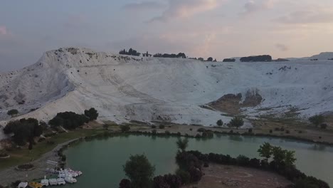 Rising-pedestal-shot-over-the-lake-during-sunrise-on-a-famous-tourist-destination-in-Turkey,-Pamukkale-carbonate-mineral-terraces