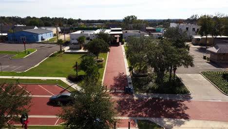 Drone-push-in-above-large-walkway-as-car-zooms-past-on-empty-road,-Clermont-Florida