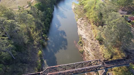 Flying-Above-Railroad-Bridge-On-Richmond-River-With-Wood-Pilings-Underneath