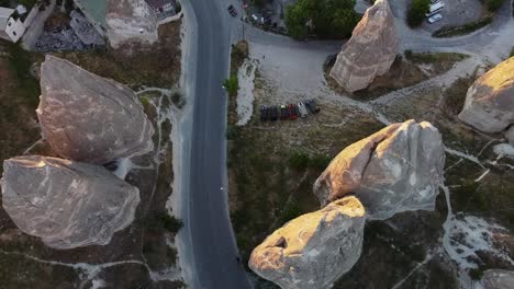 Top-down-view-of-a-busy-street-between-cone-shaped-rock-formations-in-Cappadocia,-Turkey