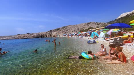 Croatia,-Krk,-Stara-Baška,-Zala-Beach,-colorful-small-bay-with-bathing-and-relaxing-people-on-holiday