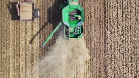 Overhead-aerial-of-harvester-unloading-to-mobile-bin-and-then-retracting-the-unloading-auger
