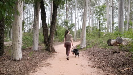 Afternoon-walking-of-a-girl-with-her-Australian-shepherd-dog-on-a-dirt-path-outdoors