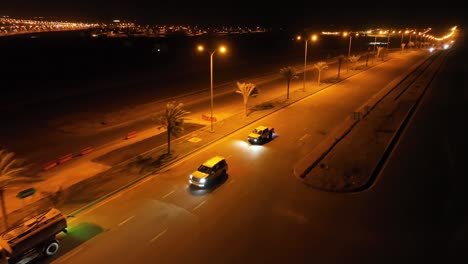 Aerial-of-cars-driving-at-night-on-light-up-road-in-Bahria-town-in-Karachi,-Sindh-Pakistan