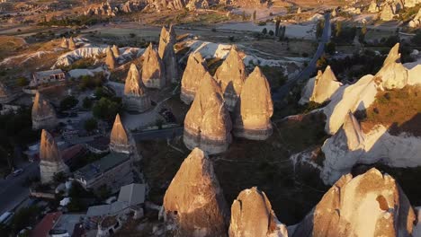 Birds-eye-view-on-fairy-chimney-rock-formations-during-golden-hour-in-Cappadocia,-Turkey