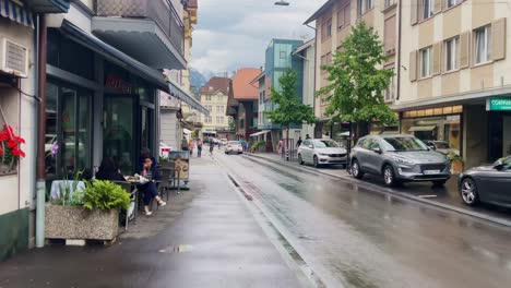 Interlaken-Switzerland-Immersive-Travel-Tourism-Mountainside-Valley-Resort-City,-Europe,-Walking,-Rainy-Day,-4K-|-Looking-Around,-Shaky,-Water,-River,-Lake,-Restaurant,-Traffic,-Tourist,-Bar,-Biker