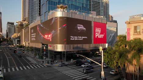 Hyper-lapse-drone-earial-of-the-largest-LED-Billboard-wall-in-downtown-Los-Angeles-california-showing-marketing-ads-along-car-traffic-and-traffic-lights-during-sunset