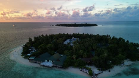 Gorgeous-Tropical-Island-Paradise-sunset---Malahini-Kuda-Bandos,-Maldives:-Aerial-drone-anticlockwise-rotate-from-low,-reveal-sun