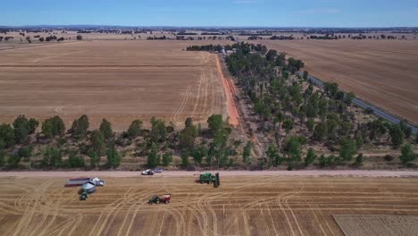 Pullback-and-descent-over-a-wheat-paddock-with-harvesting-equipment-beyond