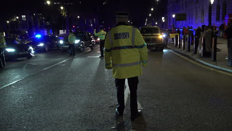 Metropolitan-police-officers-stand-on-a-road-junction-on-Parliament-Square-and-direct-vehicles-away-from-the-area-at-night