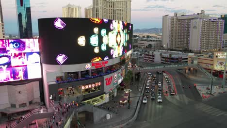 Hyper-lapse-drone-earial-of-the-largest-LED-Billboard-wall-in-Las-Vegas-Nevada-city-center-showing-marketing-ads-along-car-traffic-and-traffic-lights-during-sunset