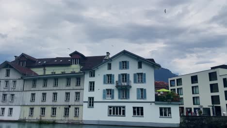 Interlaken-Switzerland-Immersive-Travel-Tourism-Mountainside-Valley-Resort-City,-Europe,-Walking,-Rainy-Day,-4K-|-Looking-Around,-Shaky,-Water,-River,-Lake,-Restaurant,-Paraglider,-Home,-Pole,-Flying
