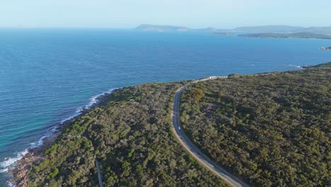 Drone-flying-over-scenic-coastal-road-at-sunset-in-summer