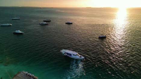 Tropical-Island-Paradise-goodbye---Malahini-Kuda-Bandos,-Maldives:-Aerial-drone-follow-guest-boat,-leaving-at-sunrise