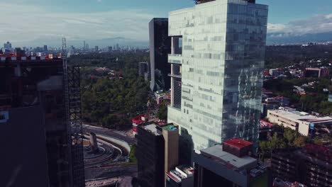 Take-between-big-buildings-of-a-panoramic-of-the-Periferico-and-Paseos-de-la-Reforma-avenues,-Chapultepec-forest,-the-National-Auditorium-and-the-Mexican-flag-are-on-the-shot