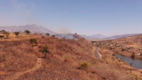 Aerial-view-towards-smoking-burning-dry-grass-wildfire-in-Monterrey,-La-Huasteca-region-of-Mexico