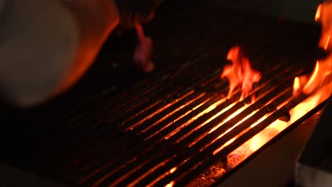 Preparing-BBQ-grill-over-sizzle-fire-in-slow-motion-by-chef-in-high-end-restaurant