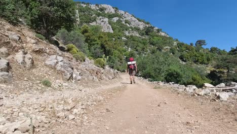 A-hiker-walking-away-while-adjusting-his-backpack-on-a-gravel-dirt-path-in-Turkey