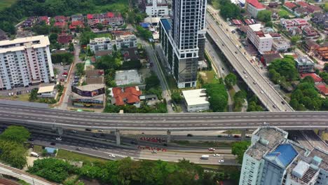 Birds-eye-view,-tilt-up-shot-capturing-complex-interconnecting-transportation-system-in-Seputeh,-Kuala-Lumpur,-Malaysia,-and-Lebuhraya-Persekutuan-highway-leading-to-Klang-with-heavy-air-pollution