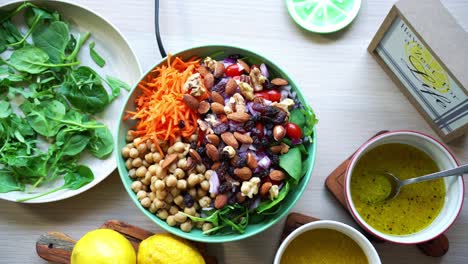 Aerial-top-view-of-chick-peas-salad-assorted-nuts-tomatoes-carrots-spinach-and-salad-dressing-on-the-side