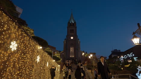 Night-View-of-Myeongdong-Cathedral-and-People-Walking-On-Stairs-and-Taking-Photos-by-the-Wall-Decorated-with-Garlands-at-sunset