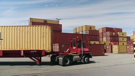Haulage-truck-carrying-shipping-container-in-Port-of-Montreal-dockyard-passing-cargo-shipment