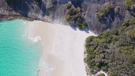 Top-down-drone-shot-of-water-lapping-against-the-white-sand-on-Misery-beach-in-Albany,-Western-Australia