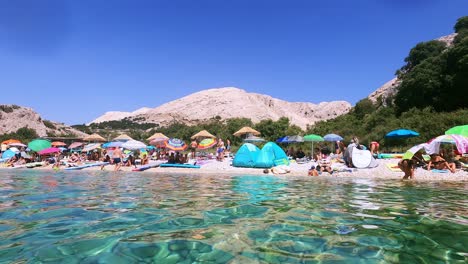 Croatia,-Krk,-Stara-Baška,-Zala-Beach-pebble-coastline-with-sunbathing-people-in-summer