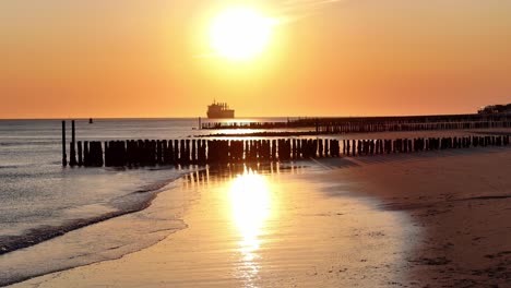 Beautiful-sunrise-scenery,-old-wooden-pier-and-backdrop-of-distant-ship
