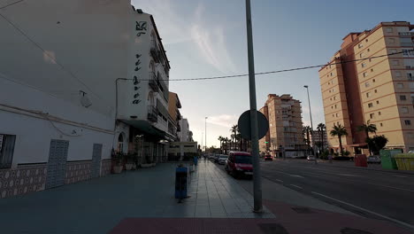 Eine-Kamerafahrt-Einer-Straße-Mit-In-Der-Nähe-Der-Gebäude-Geparkten-Autos-In-Einer-Ruhigen-Stadt-In-Spanien
