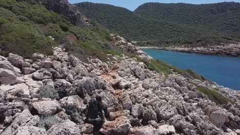 Aerial-view-of-a-long-distance-hiker-walking-along-a-rocky-path-along-the-coast-in-Southern-Turkey-on-Lycian-Way-in-spring