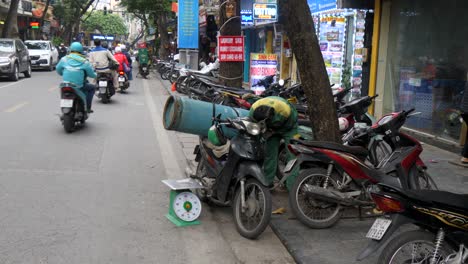 Busy-city-streets,-motorcyclist-attempting-to-safely-secure-gas-canister