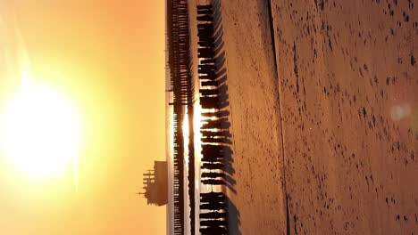Large-ship-silhouette,-golden-sunlight-illuminates-sandy-beach
