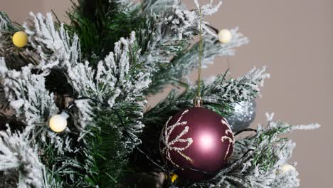 Female-hand-put-Christmas-decoration-on-artificial-Christmas-tree-branch