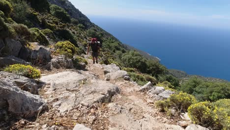 A-young-fit-male-hiker-walking-uphill-on-a-steep-climb-along-the-Mediterranean-Sea-in-Turkey