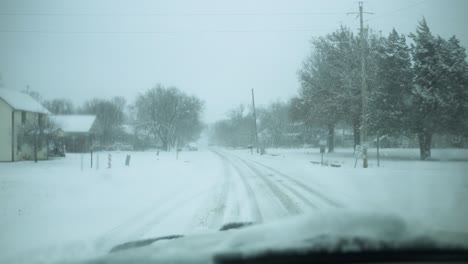 Car-driving-in-slow-motion-winter-snow-storm-as-snowflakes-fall-on-windshield-and-snow-covers-road