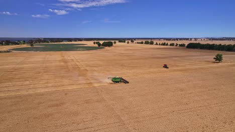 High-shot-approaching-a-harvester-working-with-paddocks-and-Lake-Mulwala-beyond