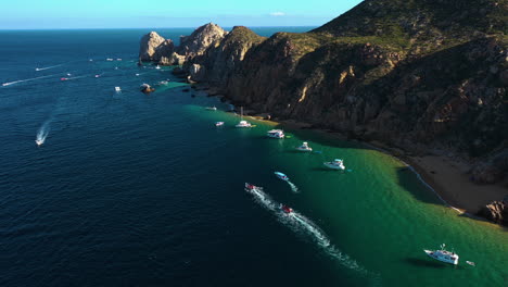 Aerial-view-following-boats-at-the-arch-of-Cabo-San-Lucas,-sunny-day-in-Mexico