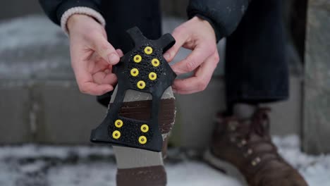 Hands-putting-ice-spikes-on-slippery-shoes-for-better-grip-on-ice,-close-up