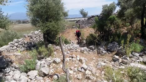 A-hiker-walking-in-the-middle-of-old-stone-walls-that-are-left-from-a-broken-down-ancient-building-in-Southern-Turkey-along-the-Lycian-Way-long-distance-hiking-trail